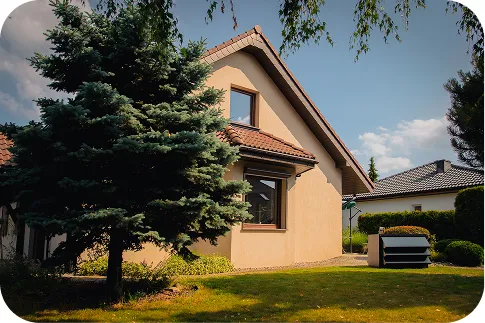 Dom jednorodzinny z beżową elewacją i pomarańczowym dachem. Obok domu, na trawniku, znajduje się pompa ciepła z nowoczesną obudową akustyczna Silencions na pompę ciepła.