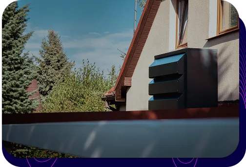 Nowoczesna, grafitowa obudowa akustyczna Silencions s|AC| zamontowana na ścianie budynku mieszkalnego, skutecznie wyciszająca klimatyzator i poprawiająca estetykę instalacji.