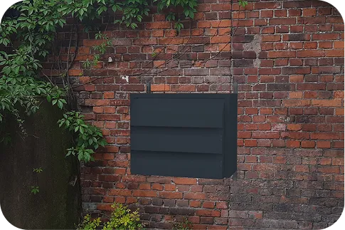 Ciemna obudowa akustyczna Silencions s|AC| zamontowana na ceglanej ścianie budynku, symbolizująca skuteczne wyciszenie klimatyzatora w obiektach hotelowych i rekreacyjnych.