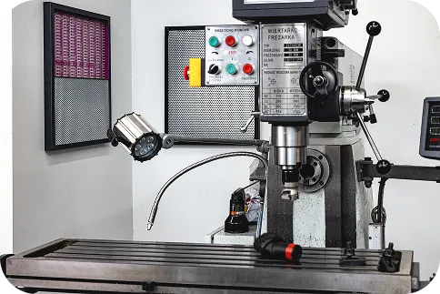 Zbliżenie na maszynę przemysłową, frezarkę, w warsztacie lub zakładzie produkcyjnym. Obraz ilustruje źródła hałasu przemysłowego, które poddajemy audytowi akustycznemu.