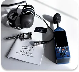 Zestaw profesjonalnego sprzętu firmy Silencions do pomiarów akustycznych: widoczny jest miernik poziomu dźwięku, słuchawki ochronne oraz inne akcesoria.