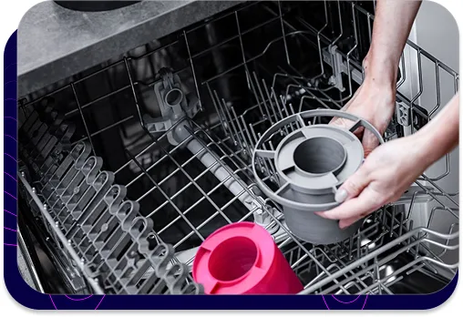 Zdjęcie pokazujące, jak tłumiki akustyczne s|TWIST są wkładane do zmywarki. Dłonie umieszczają jeden z tłumików w koszu, co demonstruje, że produkt jest wodoodporny i można go myć mechanicznie, co zapewnia łatwą konserwację.