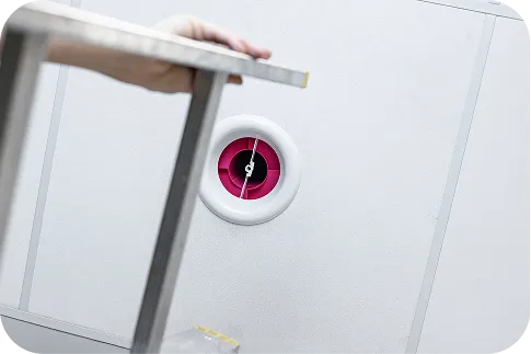 Zdjęcie ilustrujące montaż różowego tłumika akustycznego s|Twist w kratce wentylacyjnej na suficie.