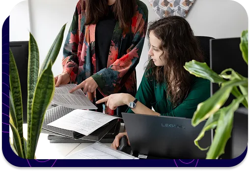 Dwie inżynierki akustyki analizujące wspólnie dokumentację techniczną projektu przy biurku.