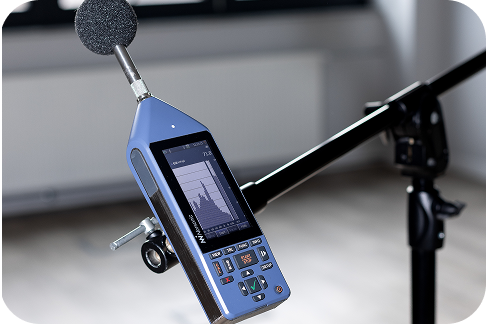 Precyzyjny miernik poziomu dźwięku klasy 1 (Norsonic) na statywie, używany do pomiarów akustyki budowlanej.