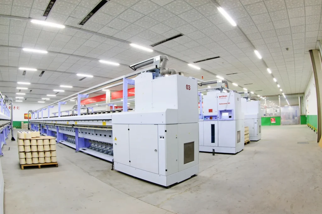 Hala produkcyjna z rzędem maszyn przemysłowych wymagających pomiarów i diagnostyki hałasu.