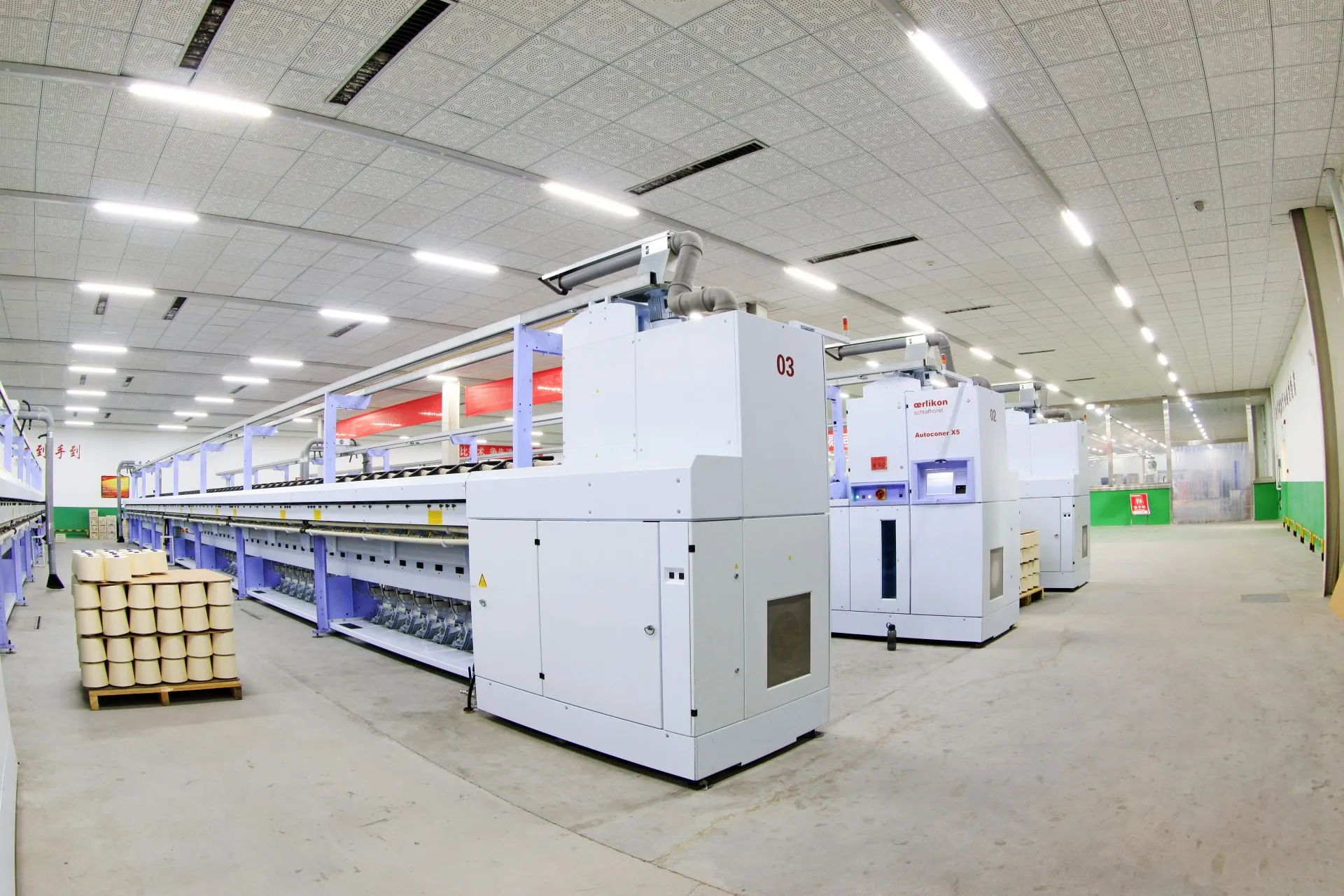 Hala produkcyjna z rzędem maszyn przemysłowych wymagających pomiarów i diagnostyki hałasu.