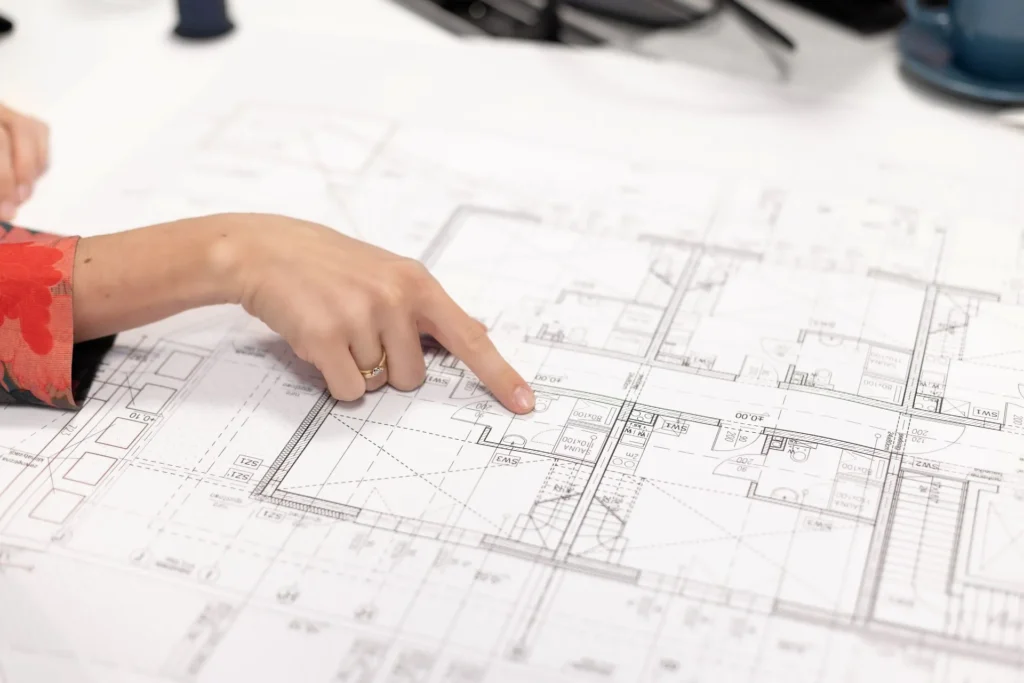 Projekt architektoniczny rzutu budynku z ręką akustyka Silencions wskazującą na szczegóły