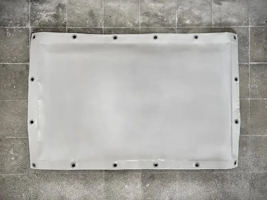 Biały panel akustyczny s|FLEX| rozłożony na płasko na szarej posadzce, widok z góry prezentujący format i rozmieszczenie otworów